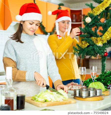 Woman with teen girl preparing christmas dinner Woman with teen girl preparing christmas dinner 75549024