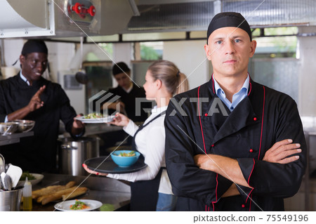 Confident male chef in restaurant kitchen Confident male chef in restaurant kitchen 75549196