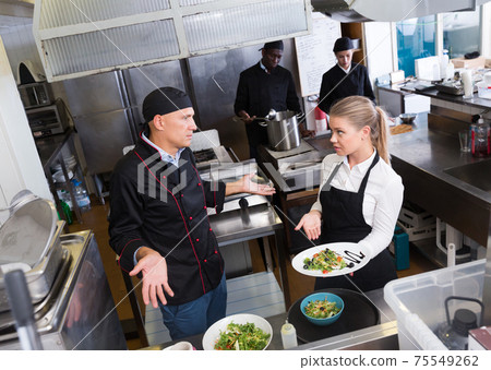 Waitress with dish talking with puzzled chef Waitress with dish talking with puzzled chef 75549262
