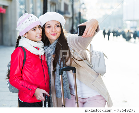 Cheerful woman with daughter making selfie Cheerful woman with daughter making selfie 75549275