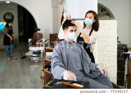 Client in mask during hair cut by professional hairdresser in mask Client in mask during hair cut by professional hairdresser in mask 75549317