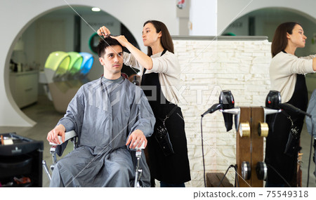 Hairdresser cut male's hair in hairdressing salon Hairdresser cut male's hair in hairdressing salon 75549318