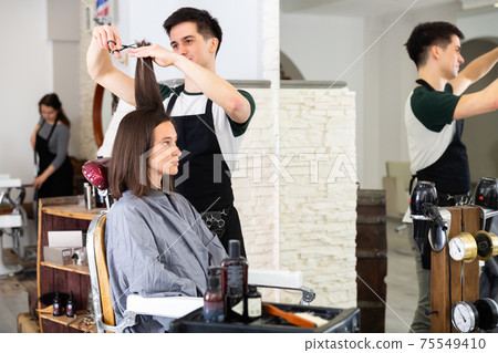 Man professional hairdresser cut female's hair in salon 75549410