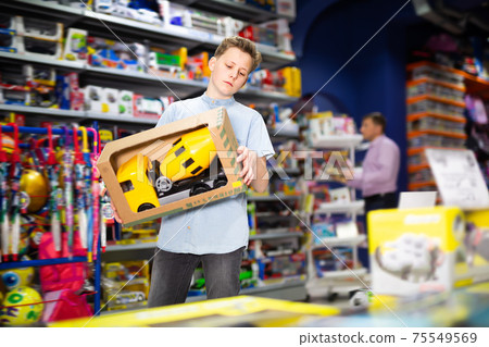 Cheery boy choosing toy cement mixer machine Cheery boy choosing toy cement mixer machine 75549569