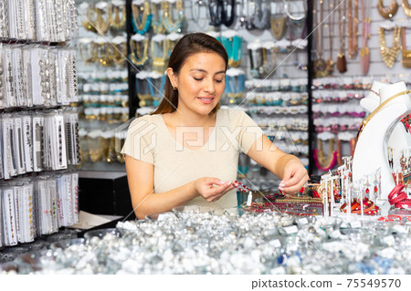 Woman chooses gemstone necklace in boutique Woman chooses gemstone necklace in boutique 75549570