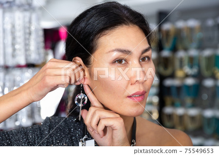 Asian woman looking for elegant earrings in bijouterie boutique 75549653
