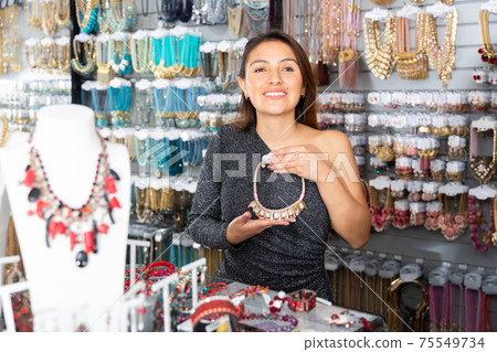 Young positive woman choosing necklace in shop 75549734