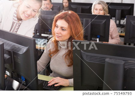Focused mature woman taking computer lessons Focused mature woman taking computer lessons 75549793