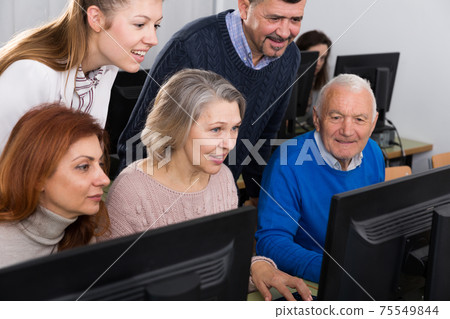Elderly people working on computer with young teacher Elderly people working on computer with young teacher 75549844