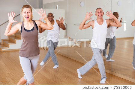 Young woman enjoying active dance with group in choreographic studio 75550003