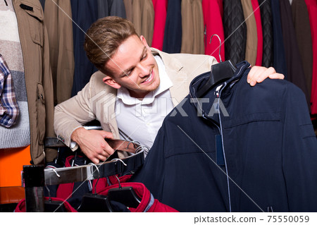 Man choosing new coat 75550059