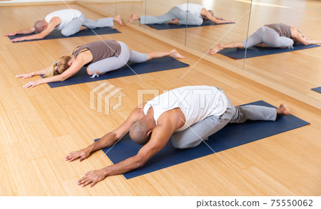 People making stretching and relaxing exercise in fitness studio 75550062