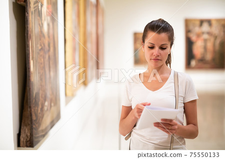 Young woman looking at artworks in museum Young woman looking at artworks in museum 75550133