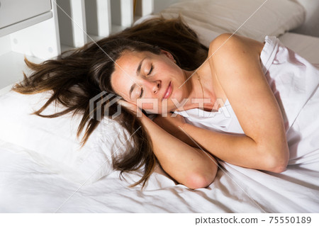 Adult female is sleeping on bed in bedroom at home Adult female is sleeping on bed in bedroom at home 75550189