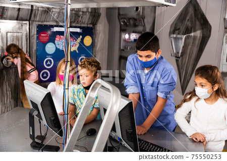 Enthusiastic children in protective masks play in the quest room of inscrutable bunker Enthusiastic children in protective masks play in the quest room of inscrutable bunker 75550253