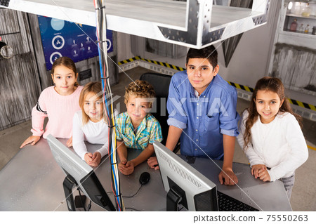 Smiling tweens standing in quest room stylized as bunker Smiling tweens standing in quest room stylized as bunker 75550263