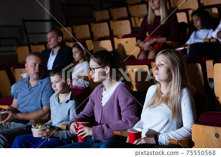 mother, father and their children sitting at film in auditorium mother, father and their children sitting at film in auditorium 75550568