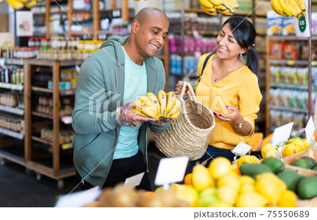 Family couple looking for ripe bananas in food store Family couple looking for ripe bananas in food store 75550689