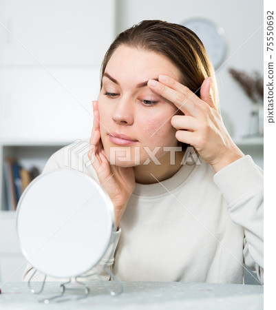 Young woman is satisfied of quality her skin in with mirror Young woman is satisfied of quality her skin in with mirror 75550692