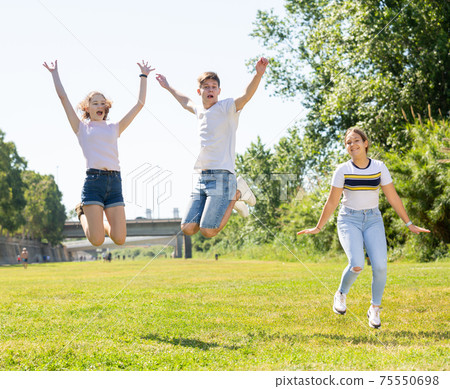 Happy teenagers jumping on the green lawn Happy teenagers jumping on the green lawn 75550698