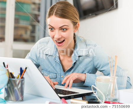 Smiling girl sitting at table at home calculating domestic finances and bills Smiling girl sitting at table at home calculating domestic finances and bills 75550699