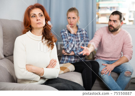 Sad mature female sitting after quarrel and daughter with boyfriend Sad mature female sitting after quarrel and daughter with boyfriend 75550887