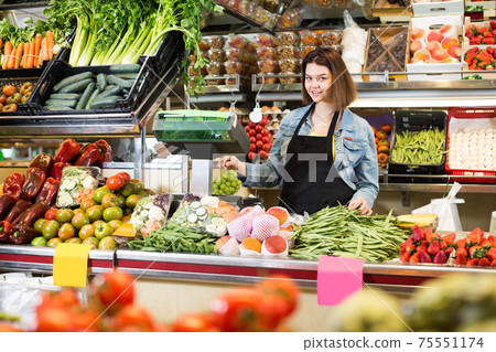 Woman seller is weighing fruit and vegetables 75551174