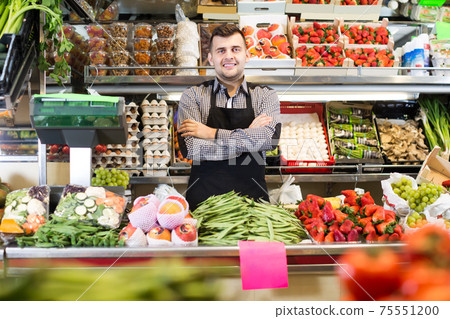 Smiling male seller showing assortment of grocery shop 75551200
