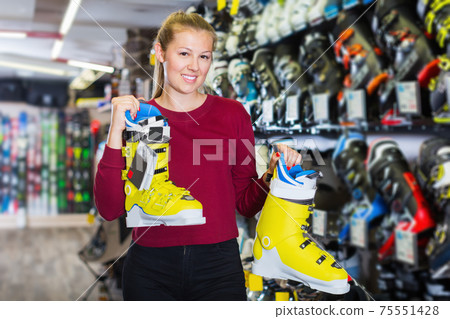 Customer woman is demonstrating new boots for skiing 75551428