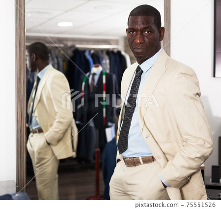 Confident male customer choosing fashion beige suit in mens store 75551526