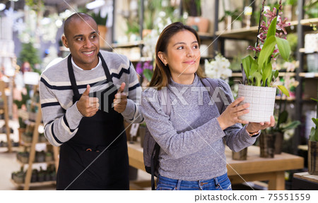 Positive woman chooses orchids in flower shop 75551559