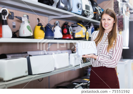 Saleswoman offering toaster in household appliances shop 75551592