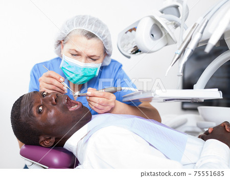 Dentist professional filling teeth for man patient sitting in medical chair 75551685