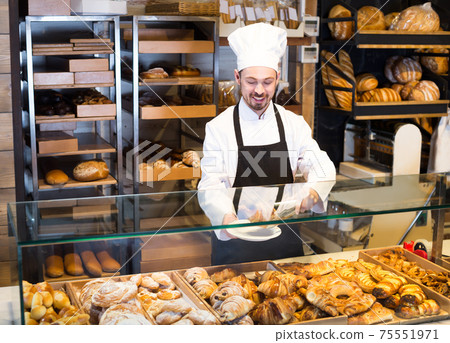 Favorable male pastry maker demonstrating croissant Favorable male pastry maker demonstrating croissant 75551971