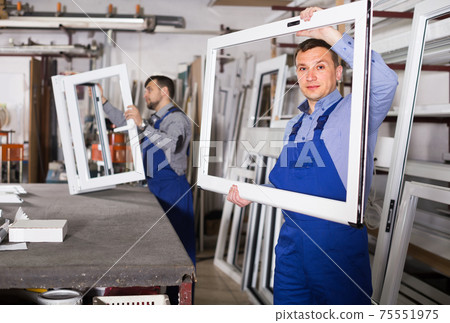 Production workers in coverall with different finished PVC profiles and windows at factory Production workers in coverall with different finished PVC profiles and windows at factory 75551975