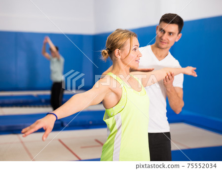 Instructor holding training with woman in trampoline room 75552034