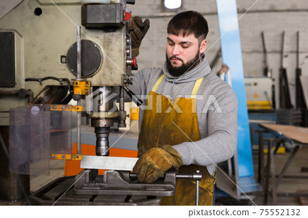 Portrait of man working with drilling machine on metal plate Portrait of man working with drilling machine on metal plate 75552132