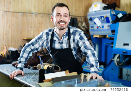 Male worker demonstrating workplace and tools in shoe Male worker demonstrating workplace and tools in shoe 75552418