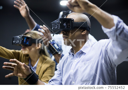 Colleagues playing video games using virtual reality glasses during team building Colleagues playing video games using virtual reality glasses during team building 75552452