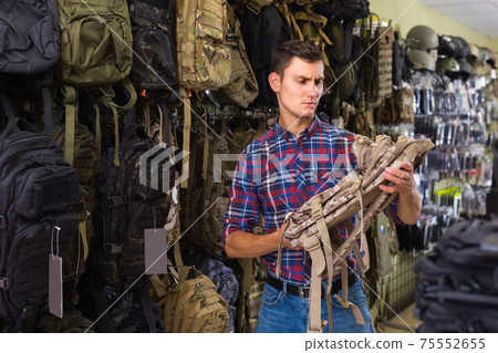 Man choosing textile backpack gun in military shop Man choosing textile backpack gun in military shop 75552655
