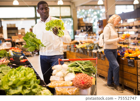 Man buying vegetables in supermarket Man buying vegetables in supermarket 75552747