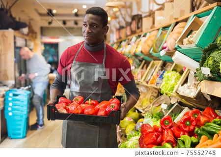 Seller arranging red peppers on greengrocery counter Seller arranging red peppers on greengrocery counter 75552748