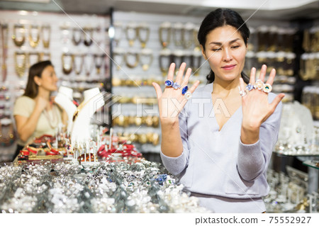 Smiling woman seller offering fashionable rings in jewelry store Smiling woman seller offering fashionable rings in jewelry store 75552927