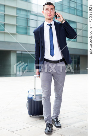 Male in suit with suitcase is calling taxi Male in suit with suitcase is calling taxi 75552928