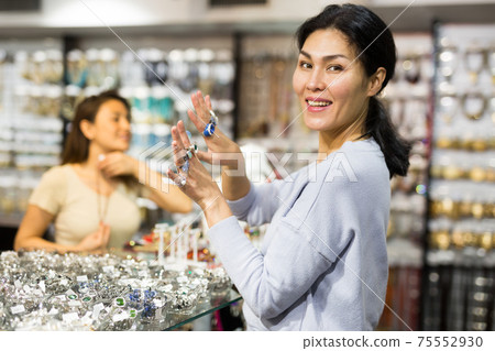 Happy asian woman showing rings in jewelry showroom Happy asian woman showing rings in jewelry showroom 75552930