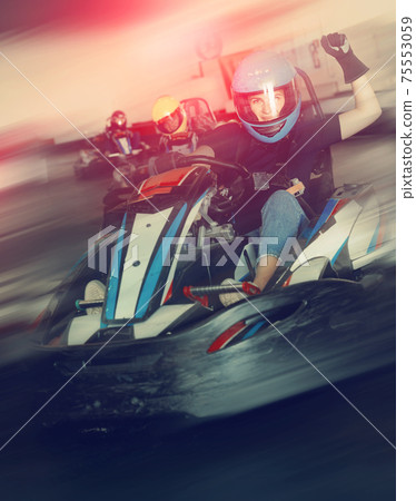 Female racer in helmet driving kart on track 75553059