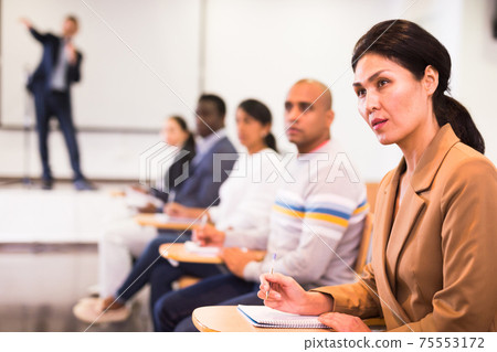 Confident woman listening to lecture at conference 75553172