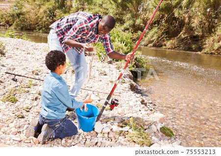 Man and boy holding fish on rod Man and boy holding fish on rod 75553213