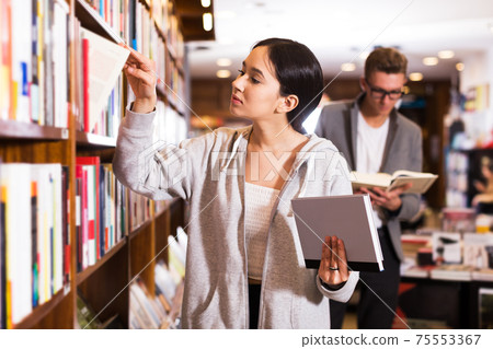 Girl searching textbooks in store 75553367