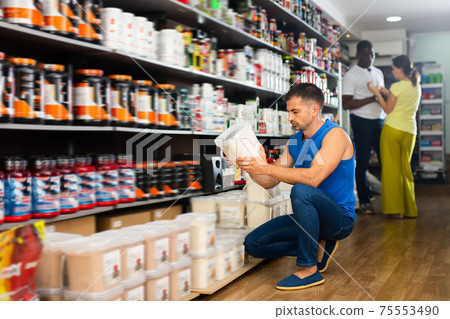 Athletic young man reading label carefully Athletic young man reading label carefully 75553490